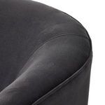 Close-up of rounded armrest and seat cushion seam with soft charcoal fabric
