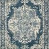 Rectangular dark blue rug with central medallion and intricate tribal-inspired abstract patterns in beige and gray