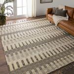 Rug displayed in a living room under natural light next to brown leather sofa and white curtains