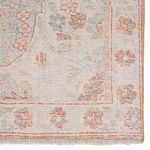 Close-up of rug corner highlighting subtle floral border and zero-pile weave in faded orange and blue hues