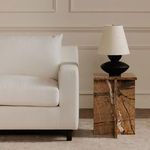 Partial view of Hutton sectional's armrest styled next to a wooden side table with lamp indoors