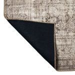 Rug corner flipped showing solid dark blue backing with brown edge stitch