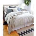 Another angle of Blake duvet on a bed with layered pillows in blue and cream, displaying relaxed folds of fabric