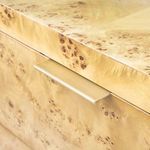 Gold-toned metal drawer handle inset above a burl wood drawer front