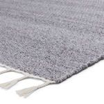 Close-up of gray woven texture and white tassels on rug edge
