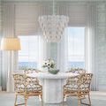 Tulum chandelier hanging above round dining table with rattan chairs and ocean view windows