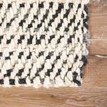 Reversed corner fold showing back side with fine diagonal weave on light wooden floor