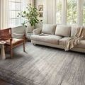 Charcoal and pebble toned modern rug styled in a bright living room under beige sofa and leather chair