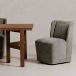 Cormac chair styled next to a wooden dining table on a neutral floor and wall backdrop