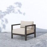 Sonoma Faye Sand Outdoor Chair placed outdoors on gray stone patio against white wall