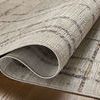 Corner of the rug partially rolled back revealing the woven backing and edge detail.