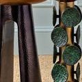 Detailed close-up of black nickel base texture contrasting with green decorative discs on adjacent table