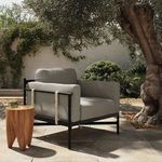 Hearst Outdoor Chair placed outdoors on patio stone flooring next to wooden side table under tree shade