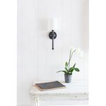 Jameson Sconce shown wall-mounted above rustic white table with plant and book in bright room
