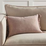 Blush pink pillow styled on beige sofa in a neutral living room setting