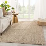 Oceana rug styled in bright room with sofa, gold side table, pouf, and greenery