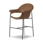 Three-quarter view showing rounded back and curved armrests of woven frame with cushion