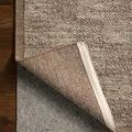 Back corner of rug folded to show woven wool underside and edge stitching detail