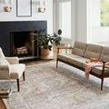 Jules Ocean Rug styled in living room with beige sofa, armchair, and black fireplace