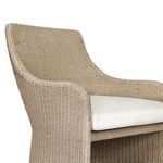 Close-up of chair arm and white seat cushion with visible woven wicker texture