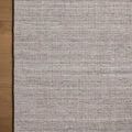 Close-up corner of rug on brown wood floor highlighting texture and weave detail