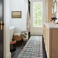 Long runner style Humphrey Plum rug in light-filled bathroom with white vanity and dark flooring