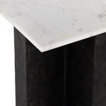 Side close-up of marble top edge and supporting black cast aluminum leg
