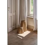 Two jute lanterns on wooden floor beside window, showing room context and natural light