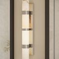 Brenham Nickel Wall Sconce mounted on beige wall with dark trim and indirect natural lighting