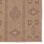 Zoomed view of Sahel rug edges showing woven tribal motifs in brown on warm natural fiber background