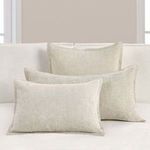 Three natural color shams styled on white sofa against beige wall for room context