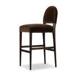 Three-quarter rear angle showing the chair’s backrest curve and supportive wooden legs with footrest bars