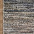 Close view of the rug’s fringed edge and intricate blend of muted tones on wood floor