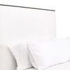 Bedroom vignette showing neutral-tone pillows, lamp, and brick wall behind Tailor Bed