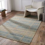 rug placed on wood floor next to cream modern armchair in bright room