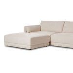 Side detail of ottoman and rounded arm with textured cream fabric and loose cushions