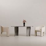 Celia Oval Dining Table styled in minimalist room setup with two cream upholstered chairs and black vase centerpiece