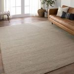 Ryker rug styled in modern living room with leather sofa, wood floor, and sunlight through glass doors