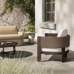 Chair positioned outdoors on a sunlit patio next to a beige sofa and tables