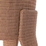 Detailed view of angled wicker leg kickback forming the chair's distinctive support