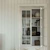 Picture light mounted above glass-front cabinet filled with books and decorative objects in living space