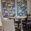 Drifting Blooms II paired in dining room setting with wooden table, beige and black chairs, and chandelier overhead