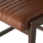 Close-up of cushioned corner of seat showing padded leather and wood edge