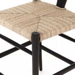 Tight close-up on corner of woven seat and top of black teak leg