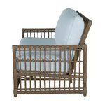 Side profile showing armrest and thick white cushions on woven wicker frame