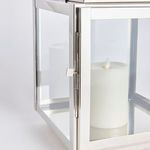 Close-up of chrome door hinge and latch on outdoor lantern with candle visible inside