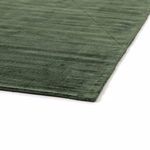 Close-up of rug corner showing smooth edge and subtle variation in green tones