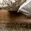 Top-down view of pillow on wooden bench with partial view of another patterned pillow