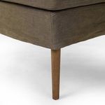 Lower corner view focusing on wood leg and fabric upholstery hem