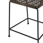 Close-up showing woven wicker seat surface and iron base support of Bandera Bar Stool